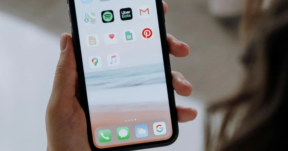 Smartphone displaying various app icons, including Uber Eats, Spotify, and Gmail, held by a hand for arranging your apps alphabetically.