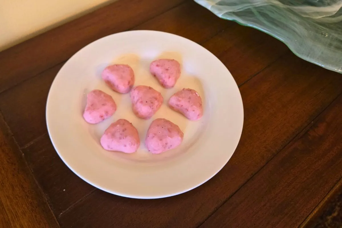 Heart-shaped, pink dessert treats arranged on a white plate.