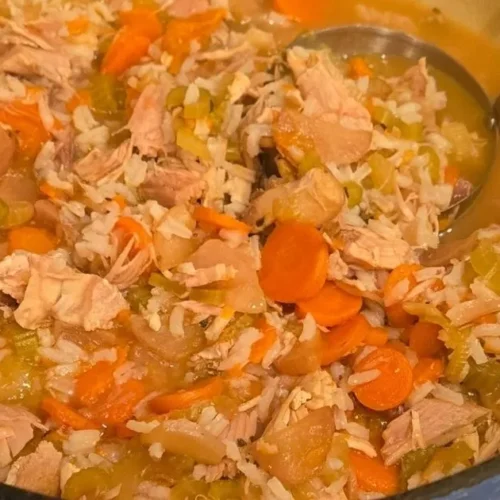 Turkey and rice soup with carrots and celery in a large pot.