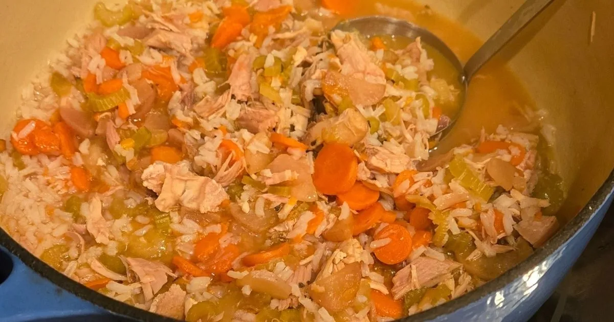 Turkey and rice soup with carrots and celery in a large pot.