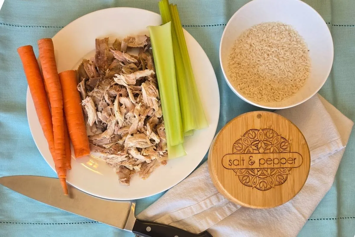 Shredded cooked turkey, carrots, celery, and rice on a plate, ready for a meal.