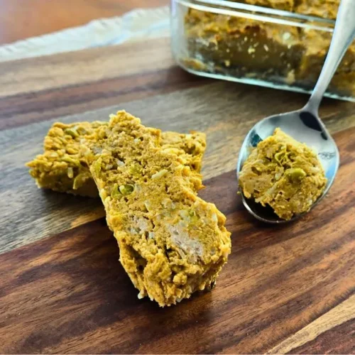 Close-up of homemade dog meatloaf slices with a serving spoon and glass container in the background.