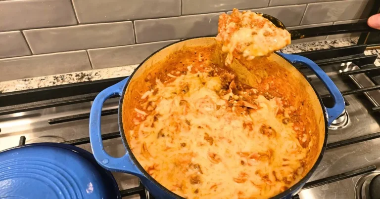 Cheesy one pot lasagna with melted mozzarella and meat sauce being spooned from a blue Dutch oven