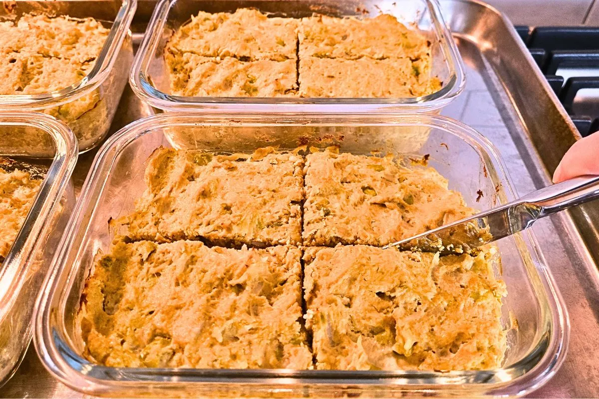 Homemade dog meatloaf being sliced into portions inside glass containers.