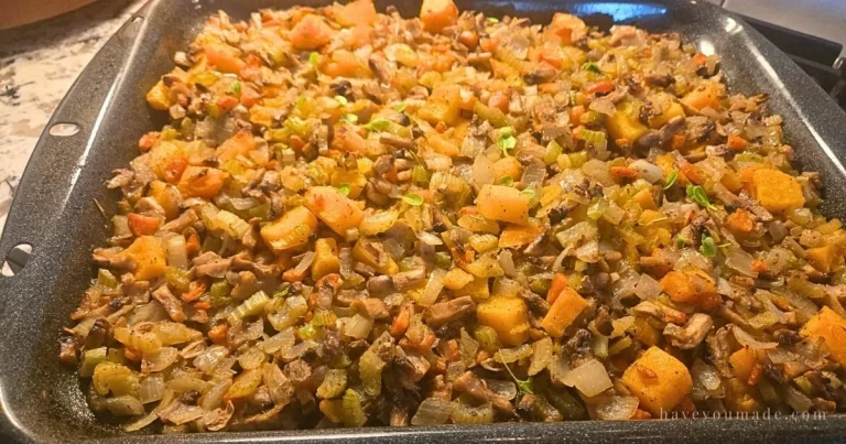 Vegetable stuffing mixture with mushrooms, onions, celery, carrots, and squash spread evenly in a roasting pan, ready to serve.