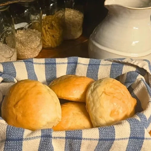 Soft homemade dinner rolls made from sandwich bread dough, brushed with butter and served warm in a lined basket